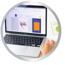 A laptop with open software displaying a heart design and an orange area. A hand is on the keyboard.