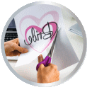 A hand is cutting a piece of paper into a heart shape with the word 'Birthday' in a creative crafting scene.