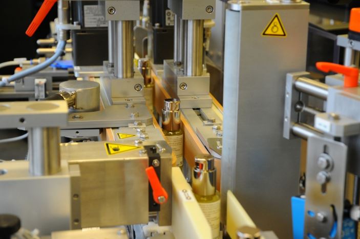 Automated machines for bottling in a production line, featuring various mechanical components and safety labels.