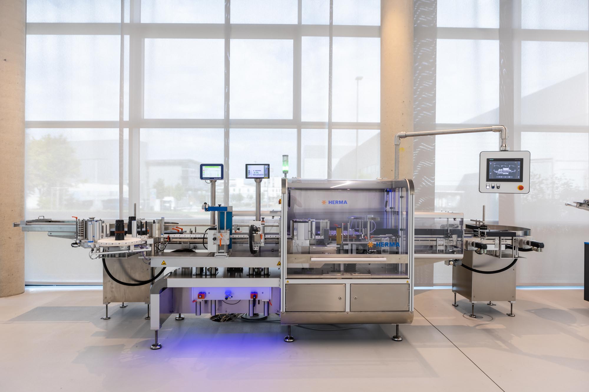 Automatic filling and labelling system in a modern production environment with multiple screens for monitoring.