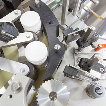 Machine for labelling bottles, equipped with various mechanical components and sensors for precise handling.