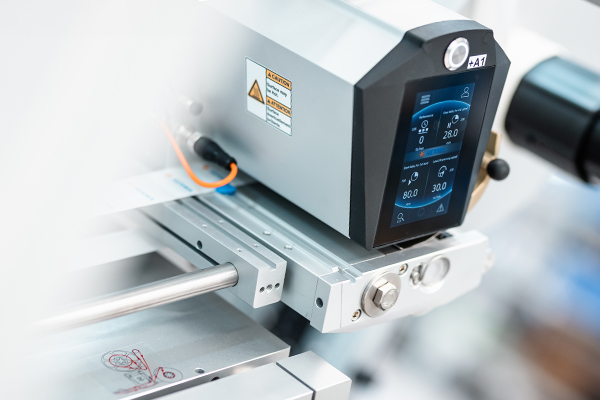 A precise control panel of a machine with digital displays for temperature and pressure, mounted on a metal structure.