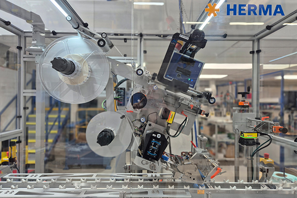 Automated labelling machine with rollers and control unit in a production environment.