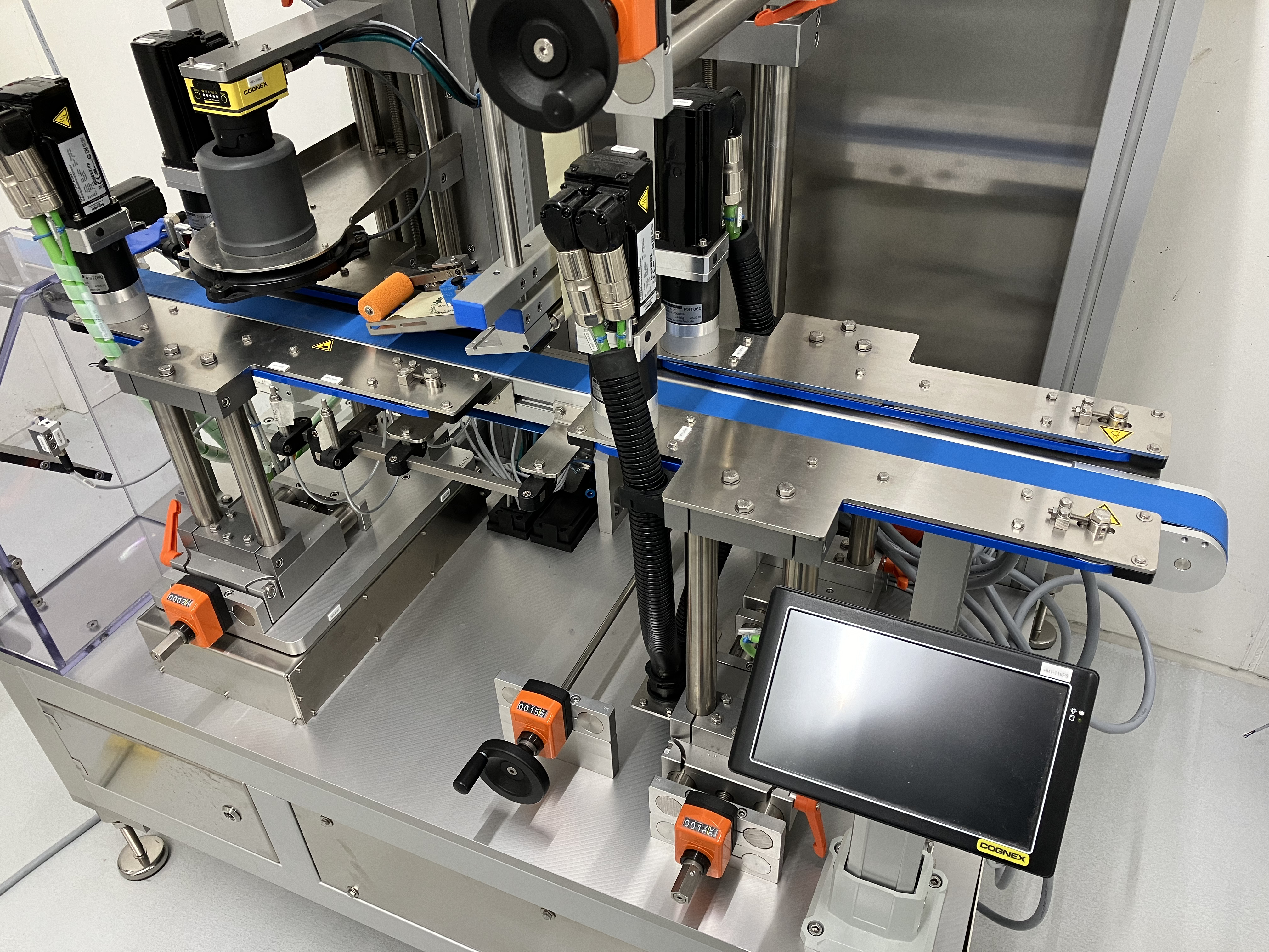 Automatisierte Maschinenanlage mit Frderband, Sensoren und Steuerungseinheit zur Verarbeitung oder Etikettierung von Produkten.