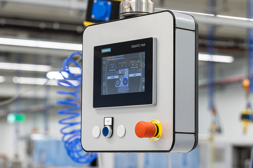 Control panel with a touchscreen and control buttons used for operating machines in an industrial setting.