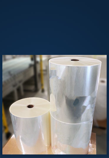 Two rolls of transparent film, one large and one smaller, are sitting on a table in a production environment.