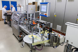 A bottling facility in a production site with employees in protective clothing handling and monitoring bottles.