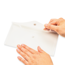 Eine Hand hält ein weißes Blatt Papier, während die andere Hand es sanft auf eine flache Oberfläche drückt.