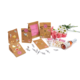 Geschenktüten mit Aufklebern, eine Flasche Sekt und Blumenarrangement, umgeben von Dekorationselementen.