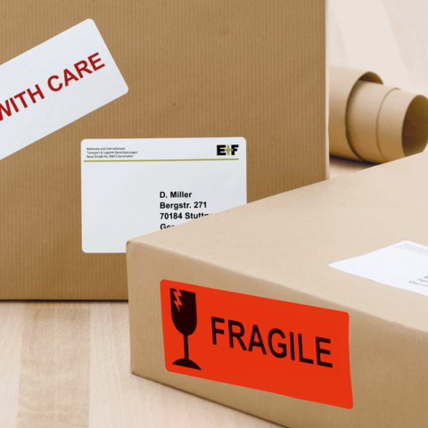 Paket mit einem Aufkleber "Vorsicht" und einem weiteren Aufkleber "Zerbrechlich", adressiert an D. Miller in Stuttgart.