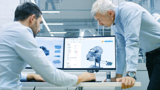 Two men are looking at technical drawings together on a computer screen in a modern office.