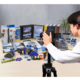 Eine Person fotografiert eine Vielzahl von Büro- und Bastelmaterialien, darunter Ordner, Kleber und Scheren, auf einem Tisch.
