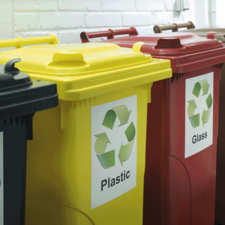 Drei Mlltonnen in verschiedenen Farben: gelb fr Plastik, rot fr Glas und schwarz fr Restmll, mit Recycling-Symbolen.