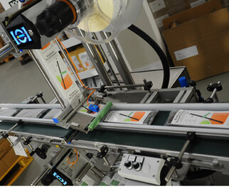 A production line with a conveyor belt, where products are moved with labels and a scanner for quality control.