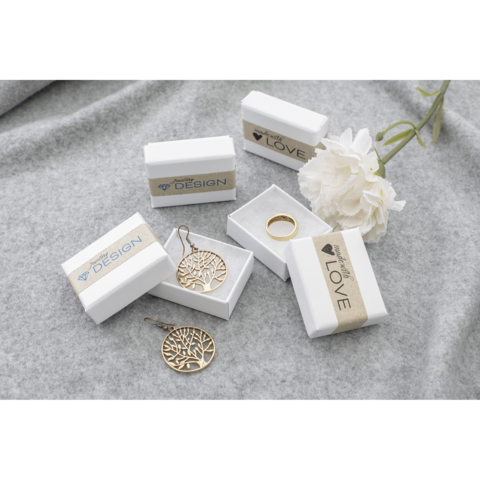 Schmuckstücke in weißen Geschenkboxen, darunter Ohrringe und ein Ring, mit einer Blume im Hintergrund.