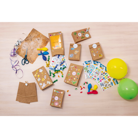 Bastelmaterialien auf einem Tisch, einschließlich Papiertüten, Aufkleber, Scheren, Ballons und bunten Bastelgegenständen.