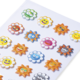 Bunte Aufkleber in Blumenform mit verschiedenen Gesichtern, darunter lächelnde und fröhliche Emojis in verschiedenen Farben.