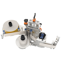 Automatic labelling machine with two rolls, a labelling mechanism, and a control panel for managing the process.