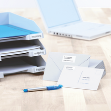 Folder with labeled sections for incoming and outgoing documents, next to it are envelopes and a blue pen on a table.