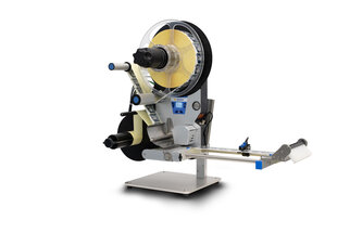 A labelling machine with rollers that applies labels to products. It features a control unit and a dispensing mechanism.