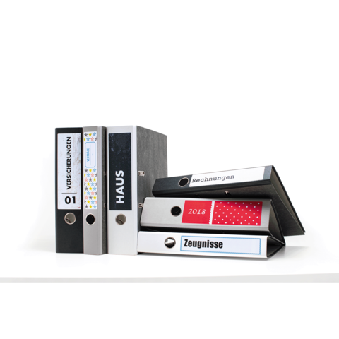 Eine Ansammlung von Aktenordnern in verschiedenen Farben, beschriftet mit "Versicherungen", "Haus", "Rechnungen" und "Zeugnisse".