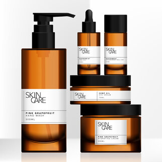 Five skincare products in brown bottles, including hand soap, oil, and creams, with white labels that read 'Pink Grapefruit.