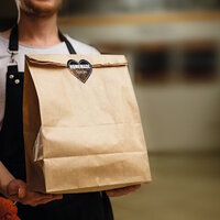 A man in a black apron is holding a brown paper bag with a sticker that says 'Homemade Spices.