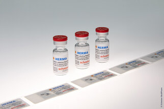 Three vials of vaccine with labels that contain information on usage and origin.