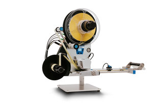 A machine device with a large spool that winds up yellow material, and a dispensing mechanism on a sturdy base.
