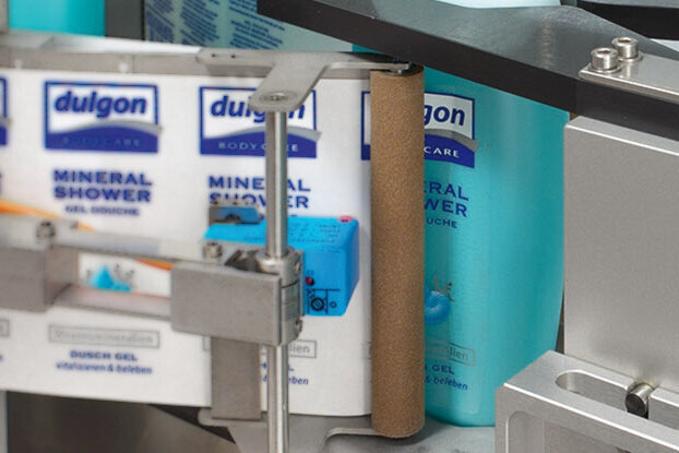 A bottle of 'Dulgon Mineral Shower' is on a production line, surrounded by other bottles of the same product.