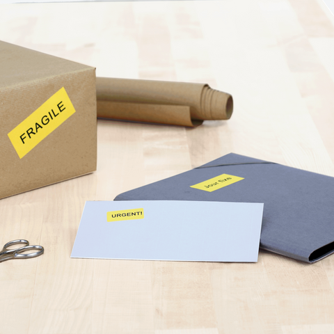 A box with the label "FRAGILE" sits next to a gray envelope marked "URGENT!" and a pair of scissors.