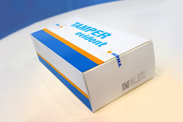 A package with the print 'TRASER' in blue and orange, placed on a light background.