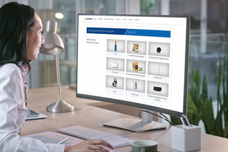 A person in a white lab coat is sitting at a desk, looking at a computer screen displaying various product options.
