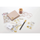 Bastelmaterialien auf einem Tisch: eine Box, goldene Aufkleber, ein Stift, eine Spule mit Schnur und verschiedene dekorative Karten.