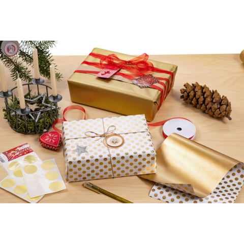 Geschenkverpackungen in Gold und Weiß mit Punkten, umgeben von Dekorationen wie Kerzen, einer Tannenzapfen und Geschenkband.