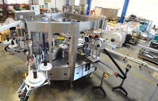 A complex packaging machine with multiple conveyor belts and labelling stations in a production environment.