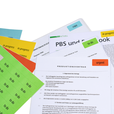 Various documents and notes with colored sticky notes, including a production contract and a working document on PBS and Facebook.