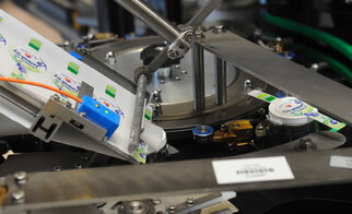 Machine for labelling bottles, with a label applied to a cap. Mechanical parts are visible.