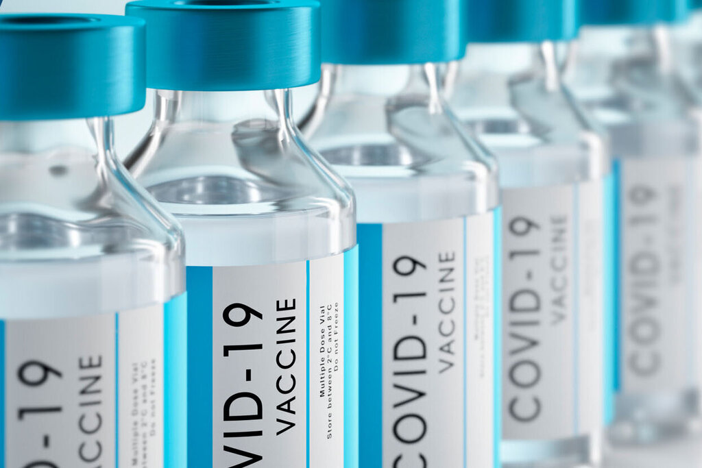 Row of vaccine vials with blue caps, labelled 'COVID-19 Vaccine.