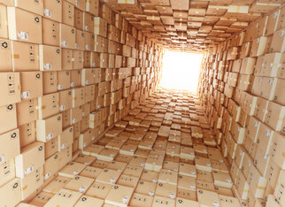 Looking up into a tower made of cardboard boxes that stretches up to the bright opening at the top.