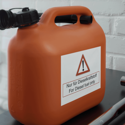 Oranger Kanister mit einem Warnschild, das besagt: „Nur für Dieselkraftstoff“ in deutscher und englischer Sprache.