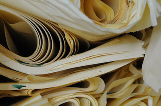 A stack of yellow, folded documents and papers, piled on top of each other and partially rolled up.