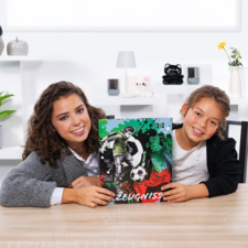 Two girls are holding a soccer report card with a graphic and a score of 3:2. They are sitting at a table in a bright room.