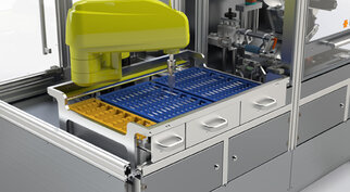 Automated laboratory device with a yellow robotic arm that handles a blue and a yellow tray for samples or materials.