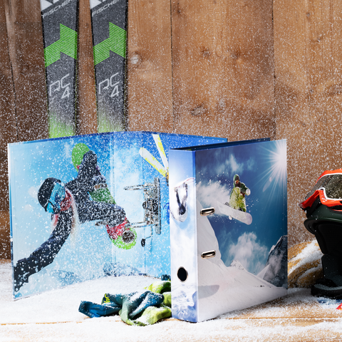 Skier in action auf einem blauen Ordner, umgeben von Skiausrüstung und Schnee, mit Skiern im Hintergrund.