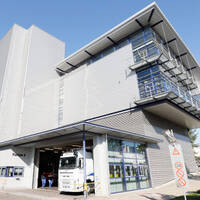Modern warehouse with a truck at the entrance and large windows. The facade is made of metal and has several floors.