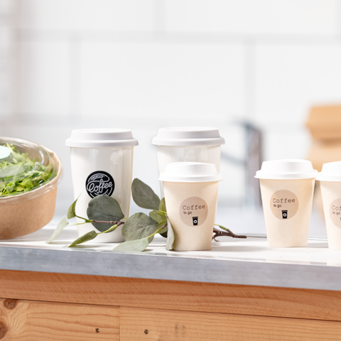 Eine Person hält ein beschriftetes Kuvert mit dem Namen "Michael Gerd" und weiteren Kuverts sowie Adressaufklebern im Hintergrund.