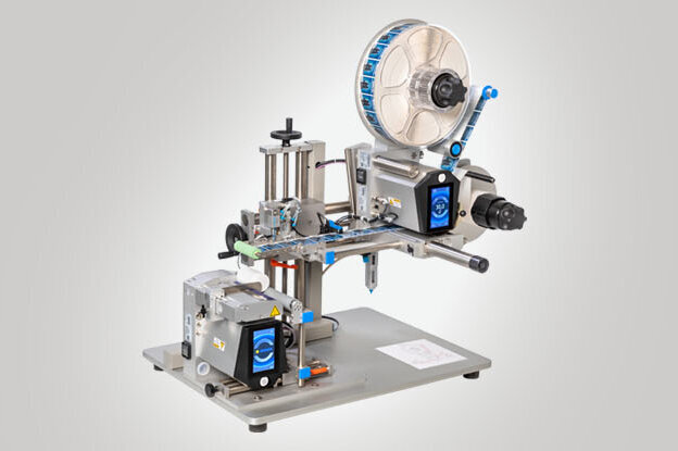 A labelling machine with various components for applying labels to products. It is mounted on a sturdy table.