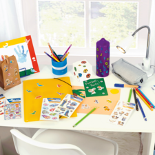 Colorfully decorated desk with craft supplies, including pens, stickers, a binder, and a lamp.