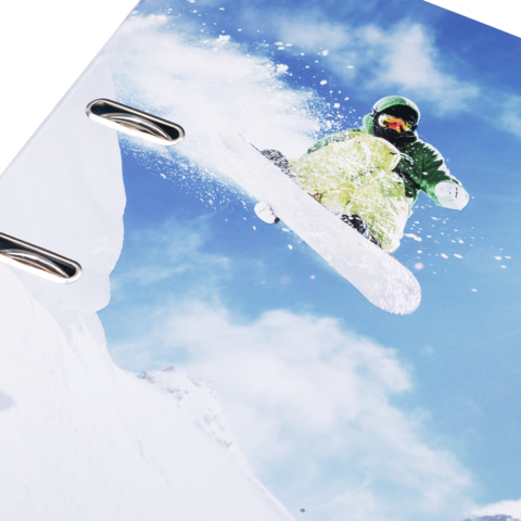 Ein Snowboarder springt über eine Schneekante, umgeben von blauem Himmel und weißen Wolken.